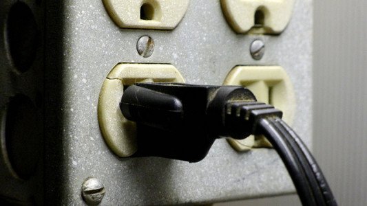 An image of a black powerplug plugged into an outlet with four ports.