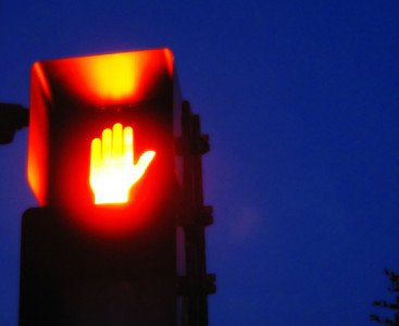 A lit red hand of a crosswalk sign.