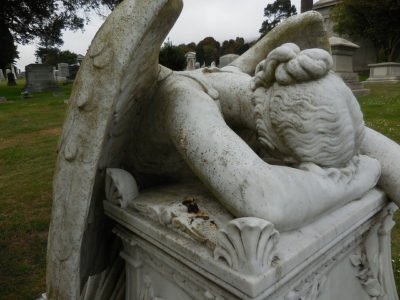 A stone angel resting her head on a plinth in apparent grief