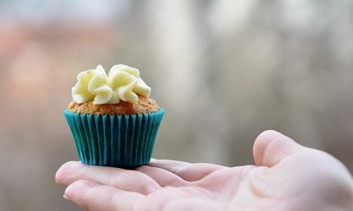 Image: hand offering a small cupcake