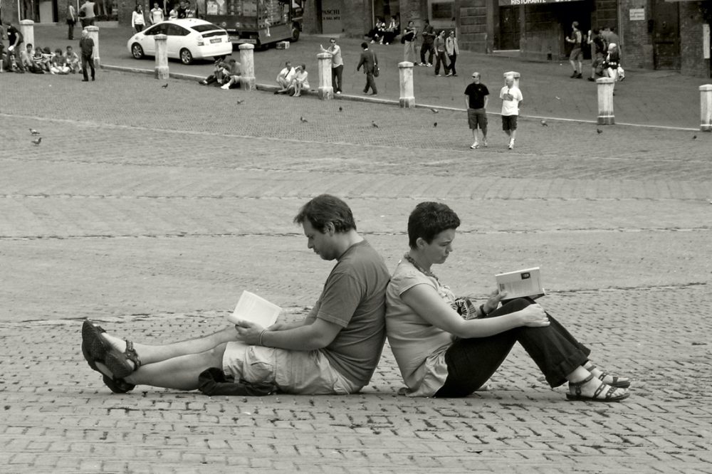 Image: book readers sitting back-to-back on the ground