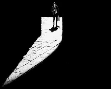 Image: man standing in comma-shaped beam of light