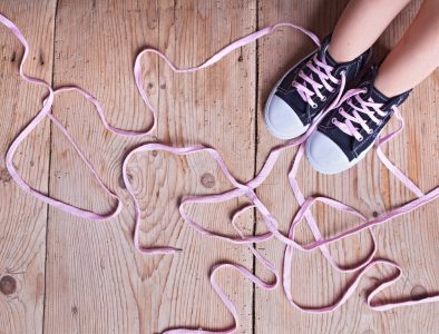 Image: a child's shoes with laces that are too long and tangled