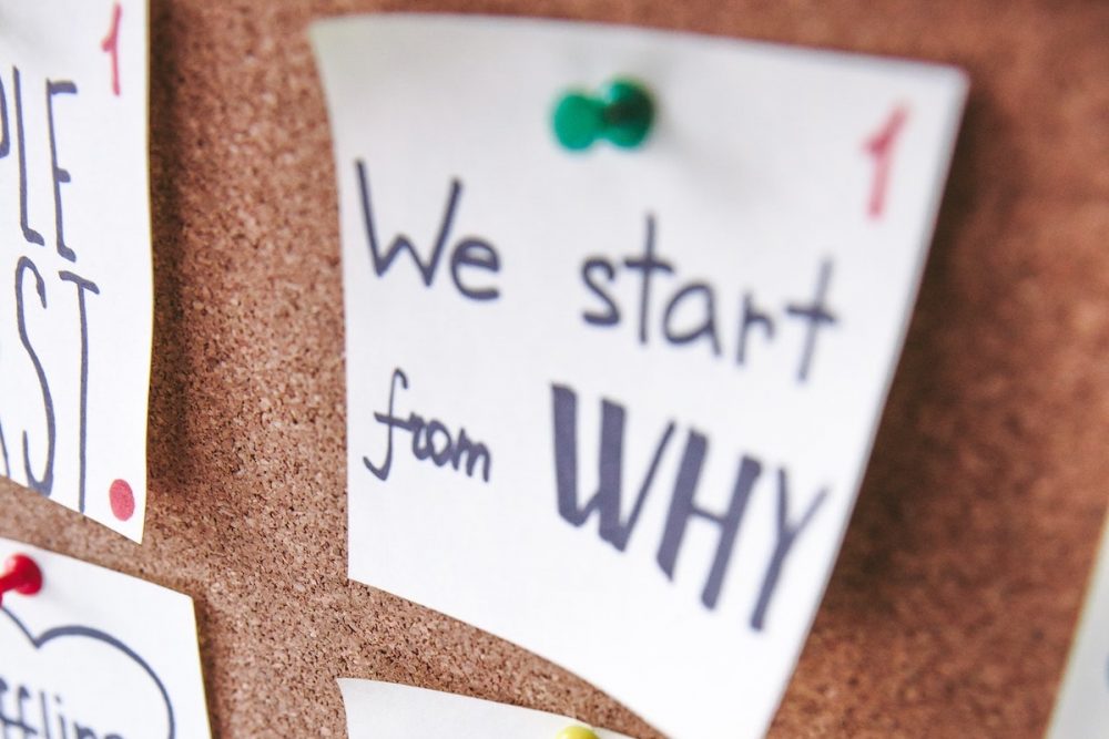 Image: a note reading "We start from WHY" pinned to a bulletin board.