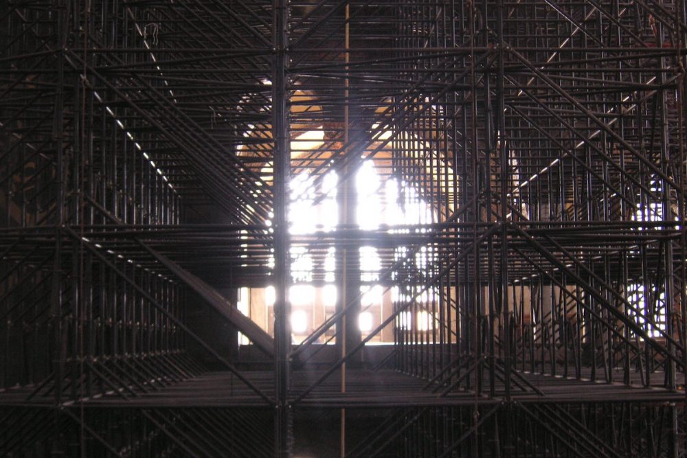 Image: dense layers of scaffolding inside the Hagia Sophia, obscuring a light-filled arched window.