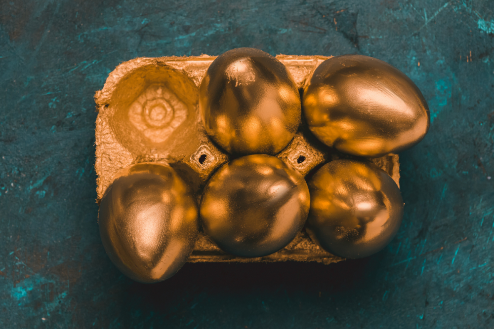 Image: six gold-painted eggs in a cardboard holder.