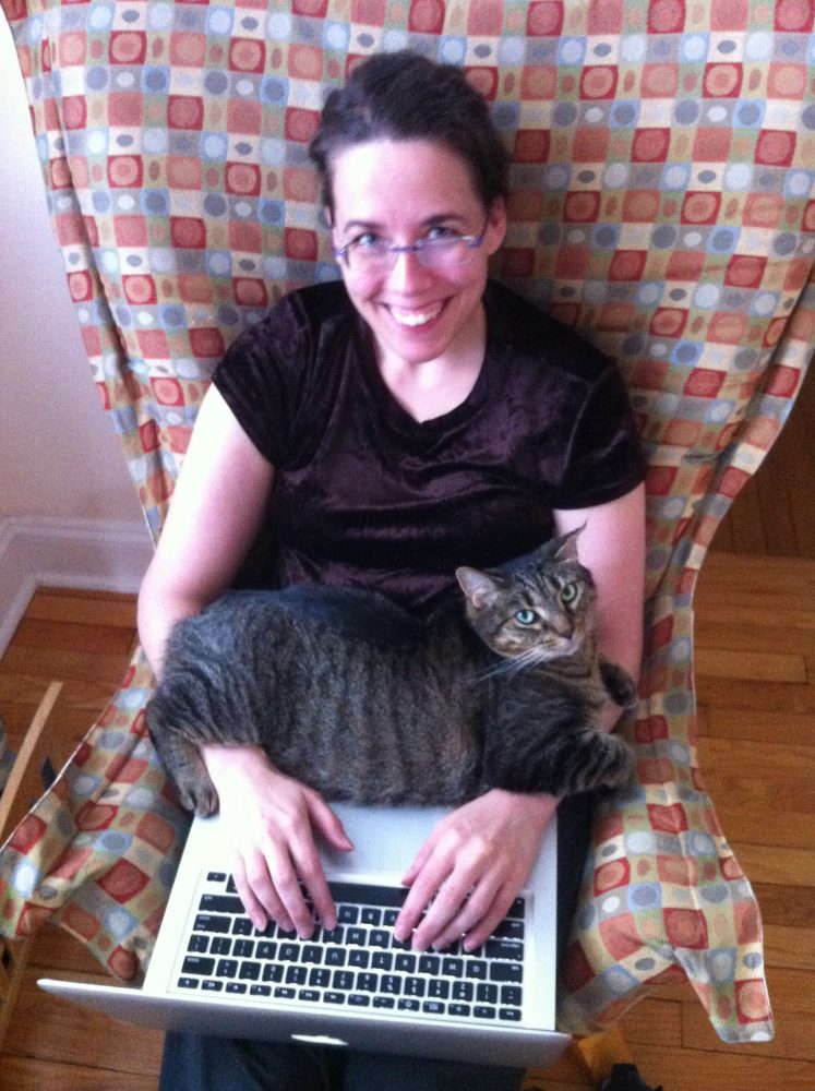 Image: Jane Friedman sitting in a chair and typing on a laptop computer; a cat, Zelda, is stretched across her arms.