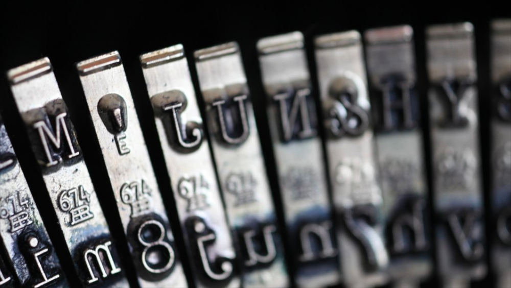 Image: close-up photo of a row of type bars from a vintage typewriter.