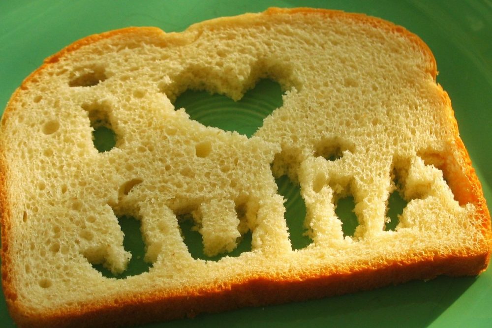 Image: atop a green plate is a slice of white bread from which holes have been cut that spell "I heart Julia".