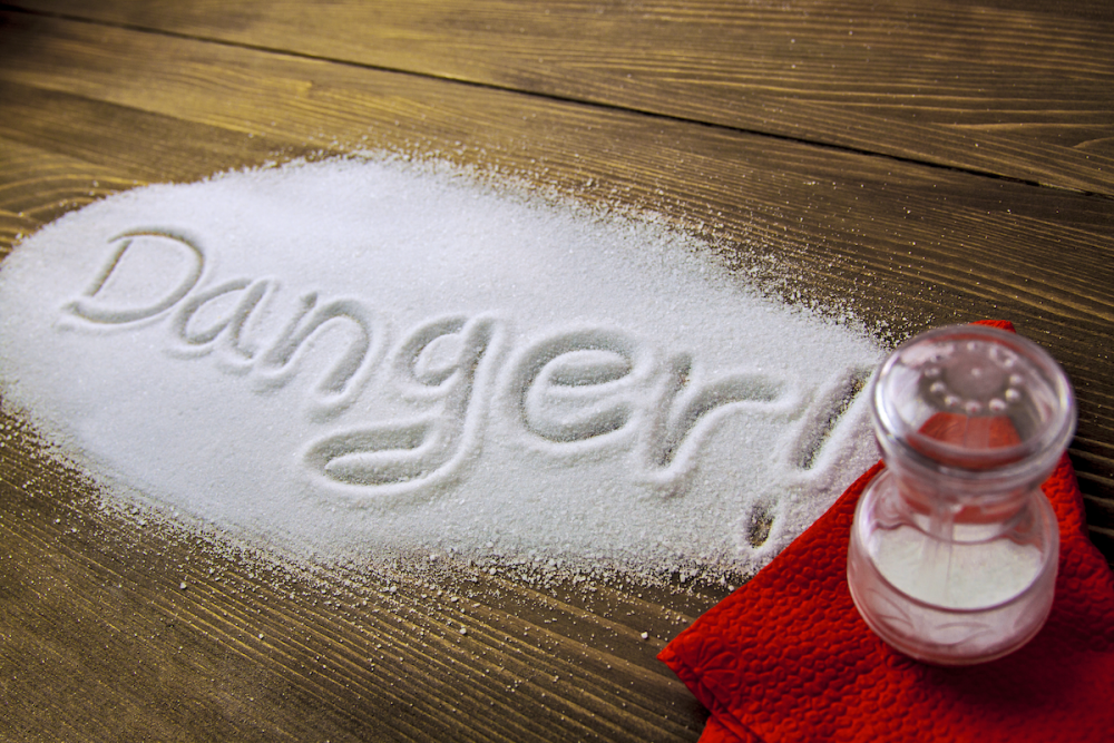 Image: the word "Danger!" spelled out in a large pile of salt spilled on a tabletop.